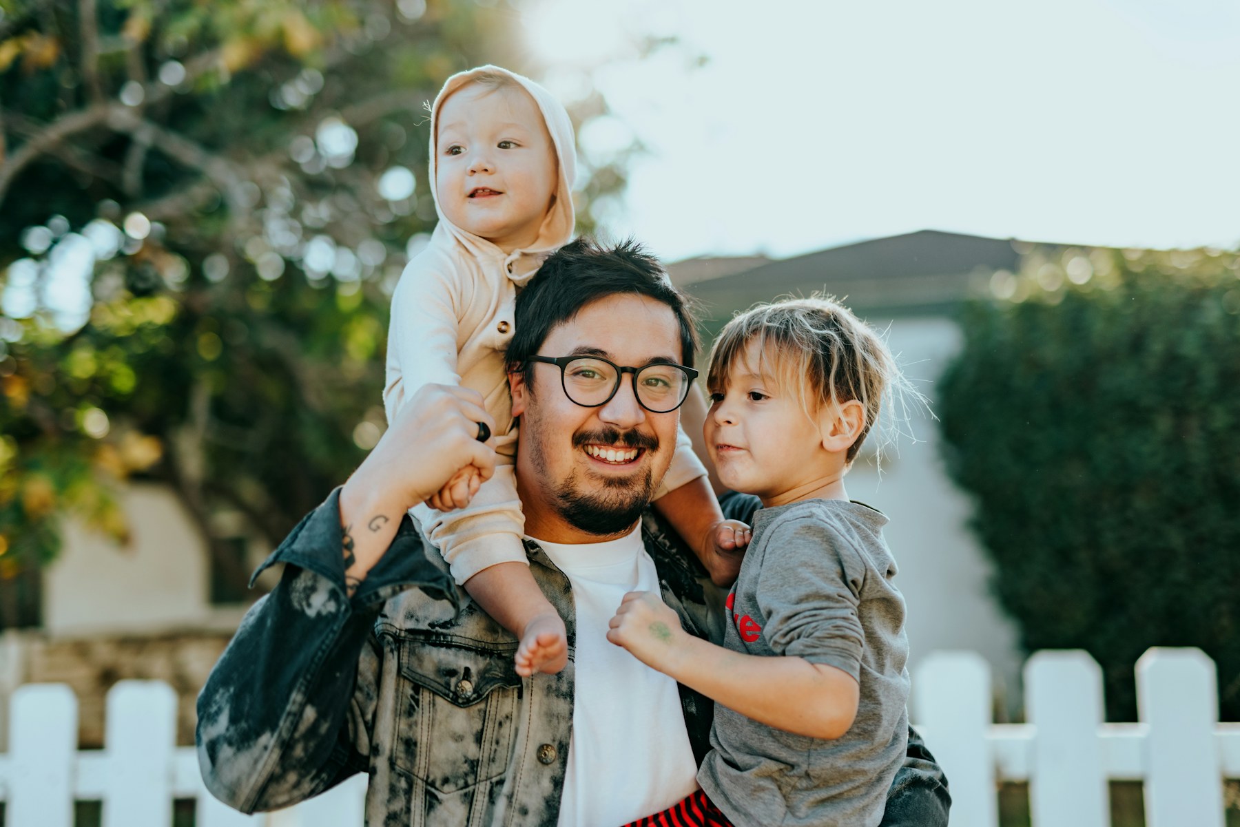 A father walking outdoors with his two young children in golden evening light